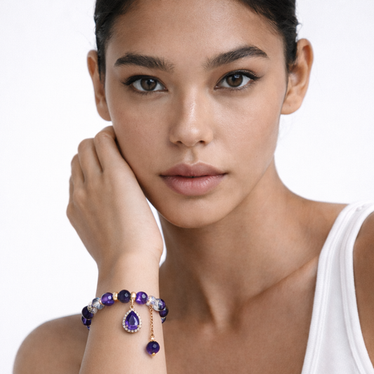 Woman wearing amethyst pendant bracelet with purple beads and gold charm jewellery