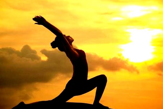 Silhouette of person in yoga lunge pose at sunrise, golden sky, sun on horizon, calm and focused atmosphere