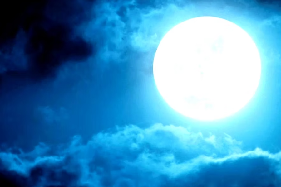 Full moon above clouds at night, blue sky background, calm atmosphere