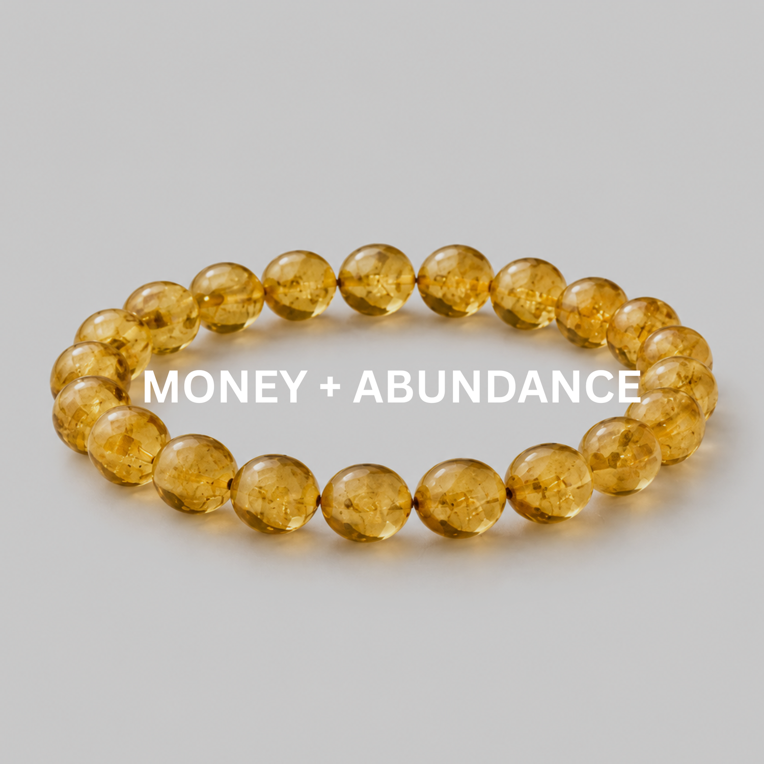 Money + Abundance bracelet collection image with golden citrine bead bracelet on light stone surface