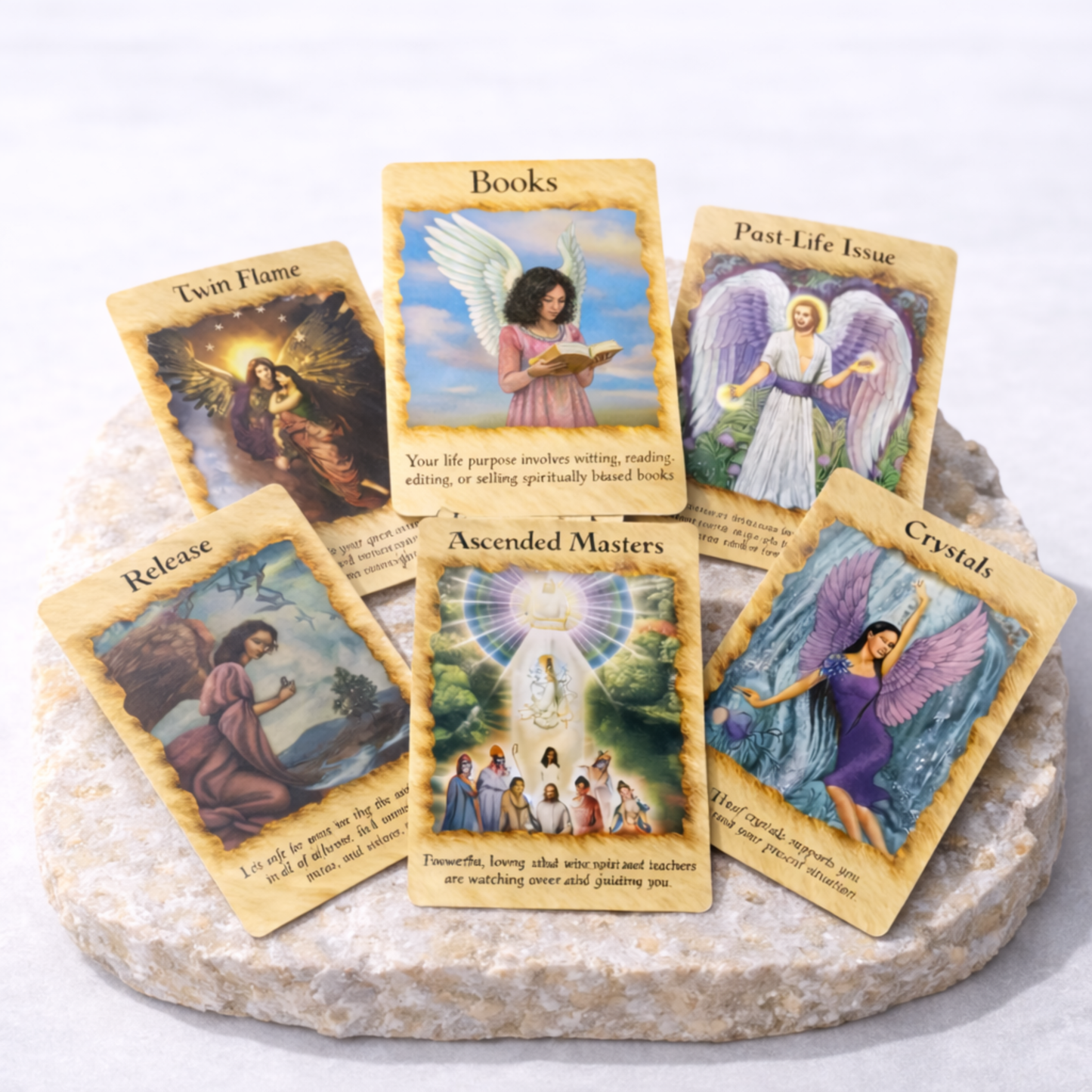 Angel oracle cards spread with Books Twin Flame Past Life Issue and Ascended Masters cards on beige stone slab