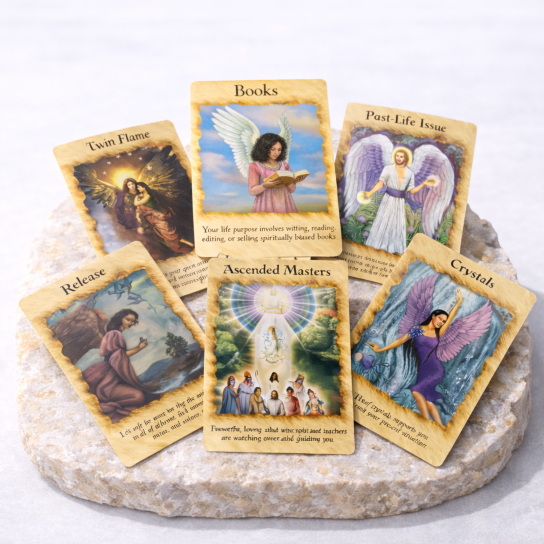Angel oracle cards spread with Books Twin Flame Past Life Issue and Ascended Masters cards on beige stone slab