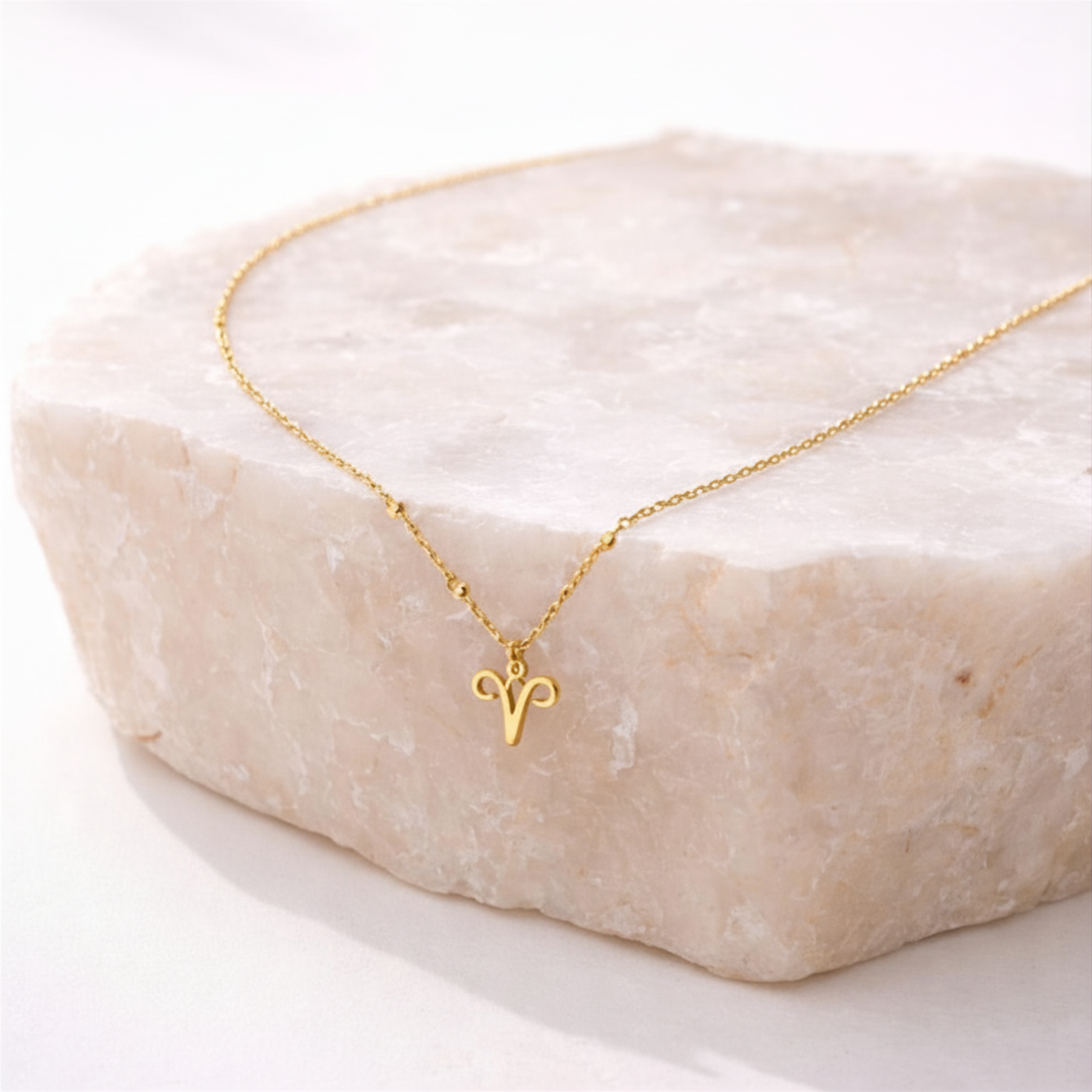Aries necklace gold zodiac symbol pendant on beige stone slab