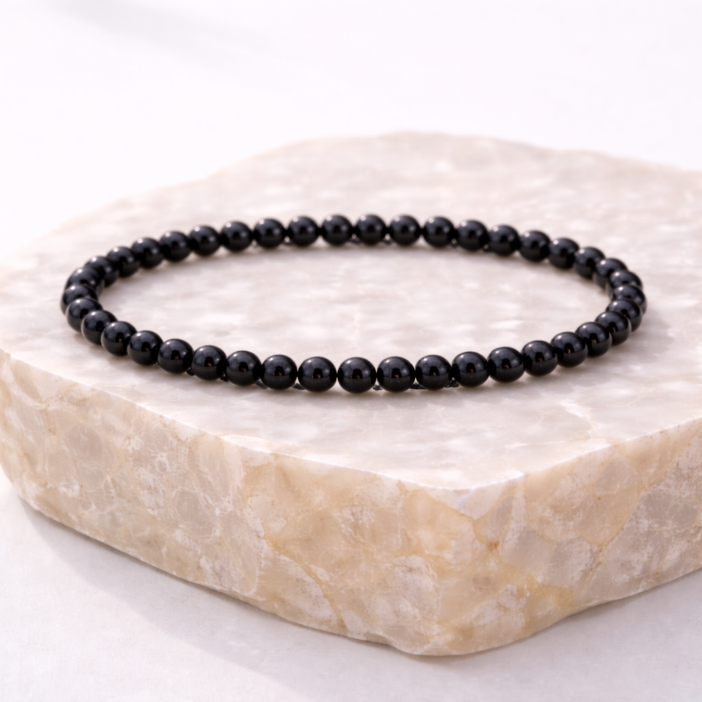 Black obsidian crystal bead bracelet on natural stone display