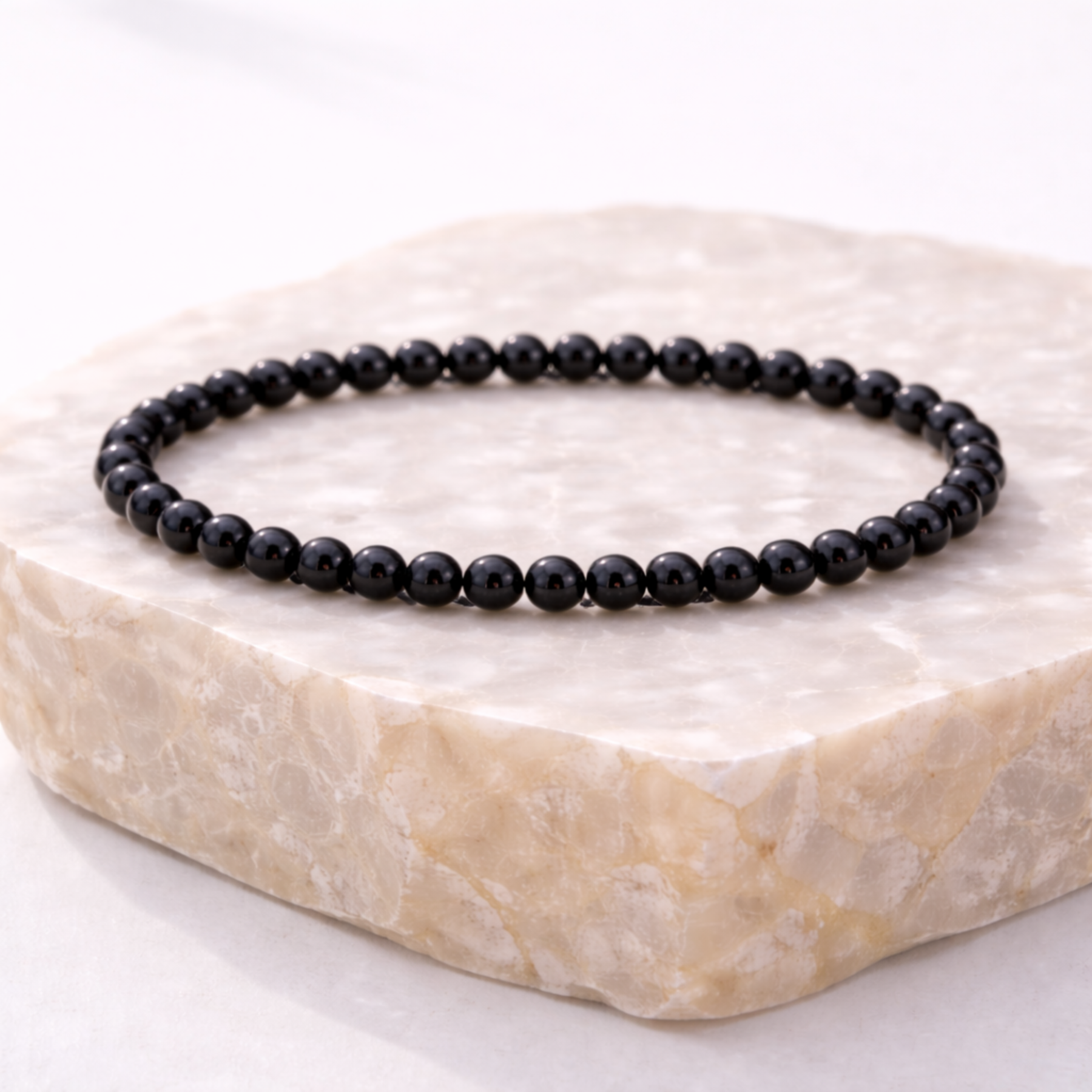 Black obsidian crystal bead bracelet on natural stone display