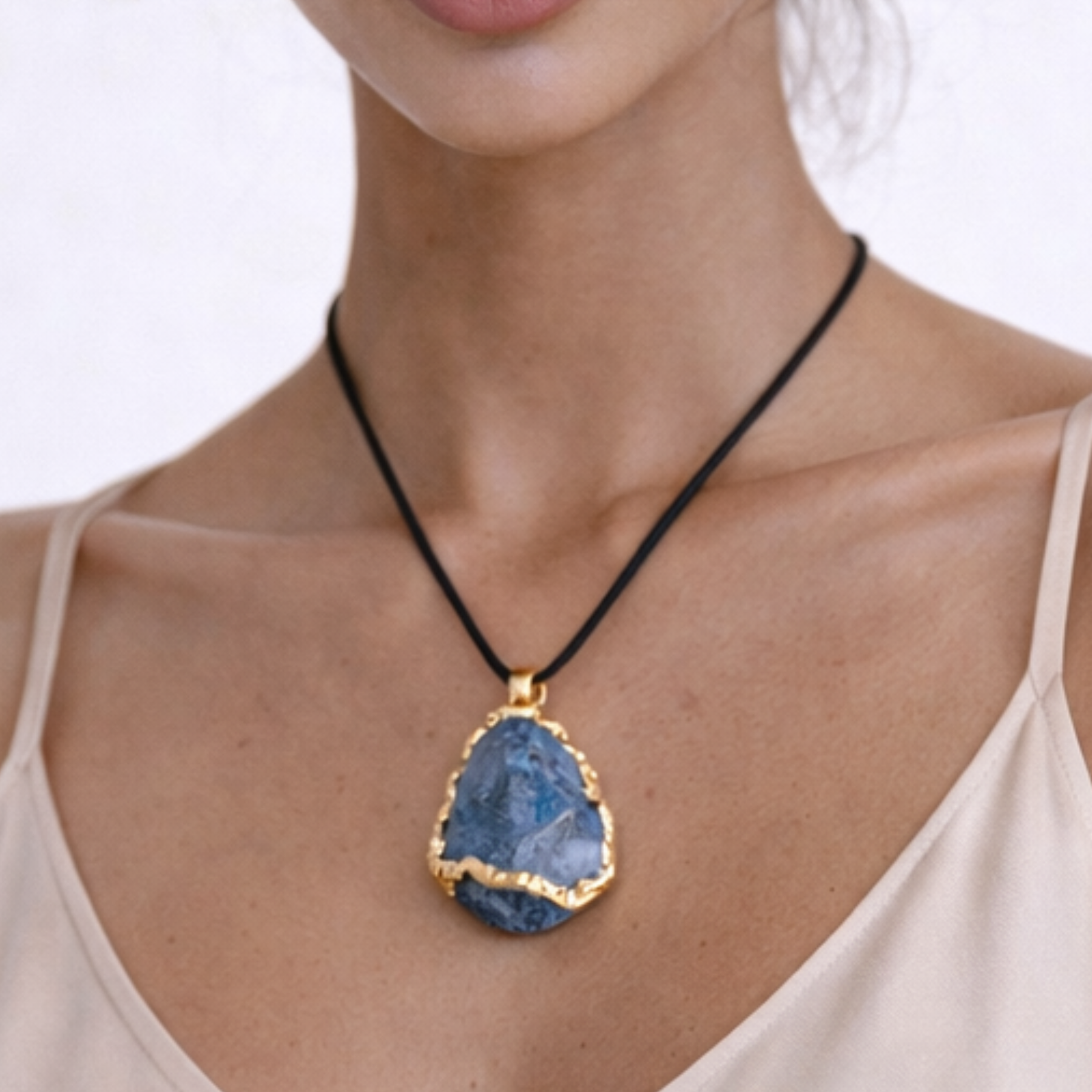 Blue apatite necklace close up on model showing blue stone pendant with gold edge