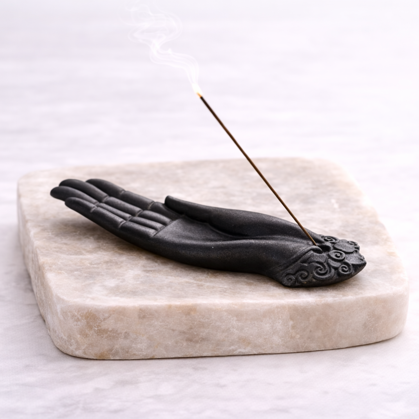 Buddha hand incense burner angled view with smoke rising on slab