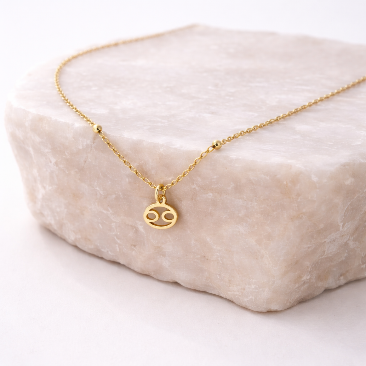 Cancer zodiac necklace gold worn on model with eyes closed and gold chain