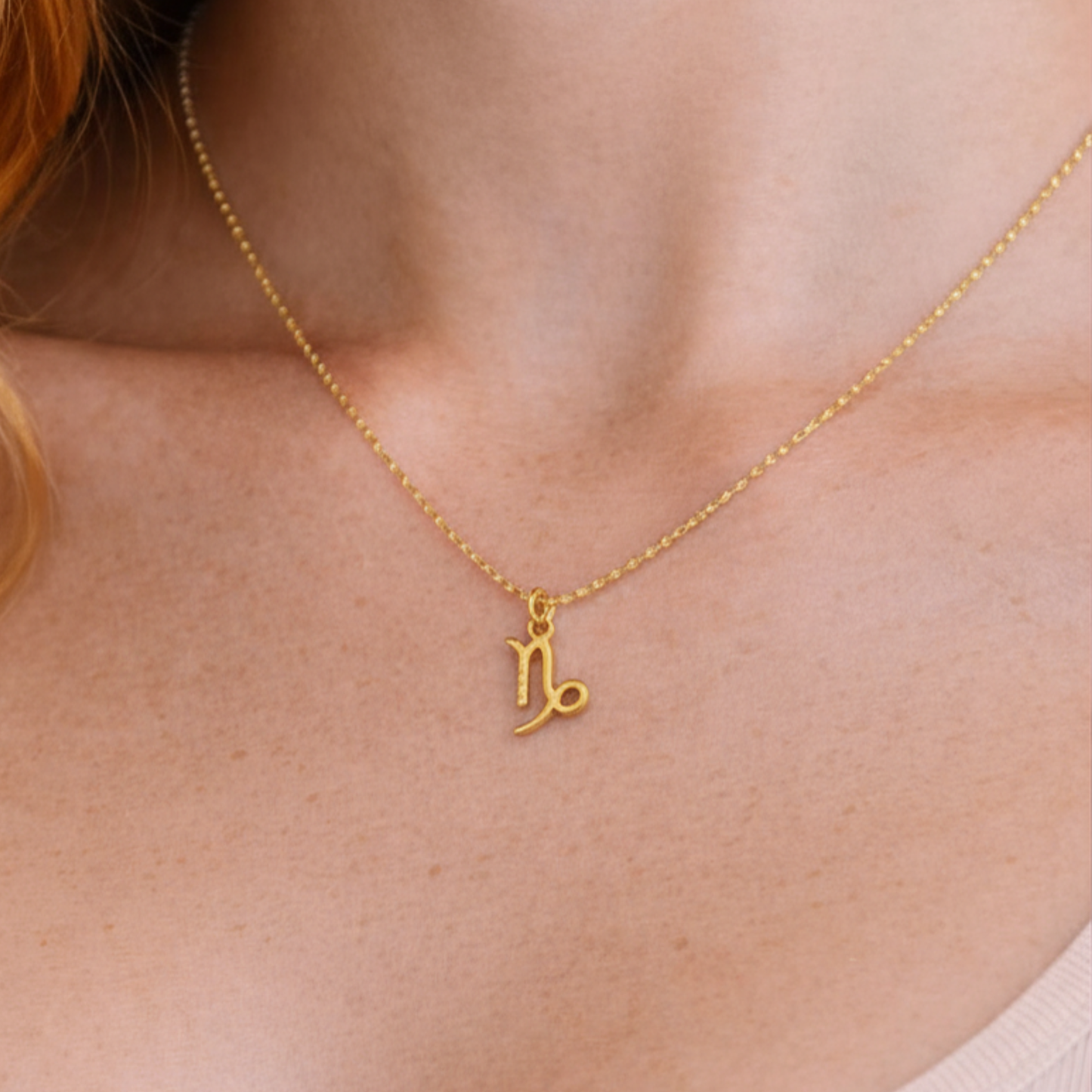 Capricorn necklace gold worn on model looking to side with gold chain