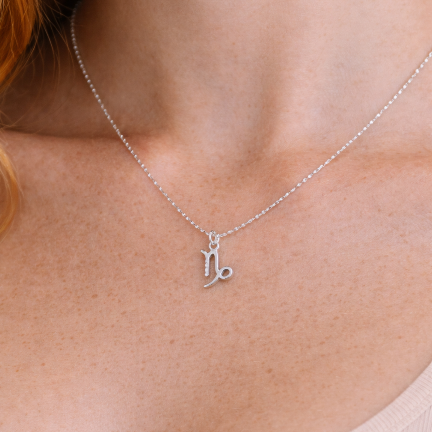 Capricorn necklace silver worn on model looking to side with silver chain