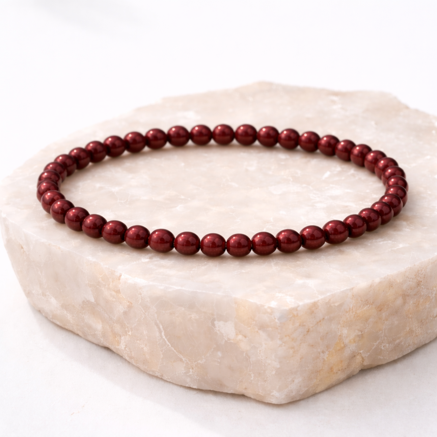 Cinnabar crystal bracelet with polished red beads on natural stone display