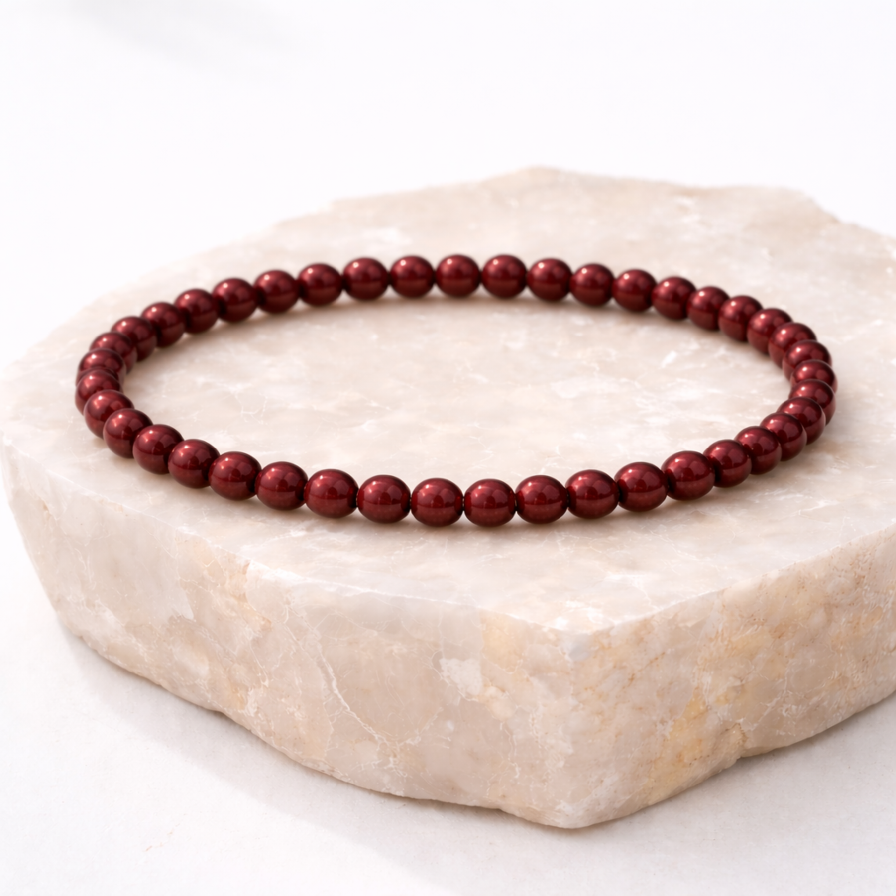 Cinnabar crystal bracelet with polished red beads on natural stone display