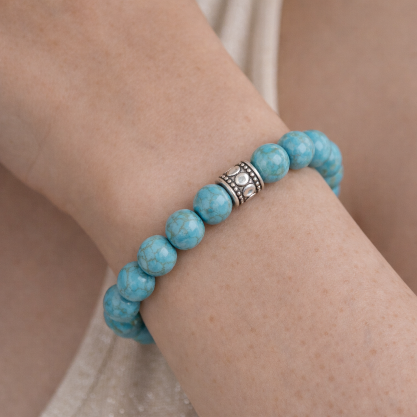 Close up of turquoise bead bracelet with silver spacer beads worn on wrist