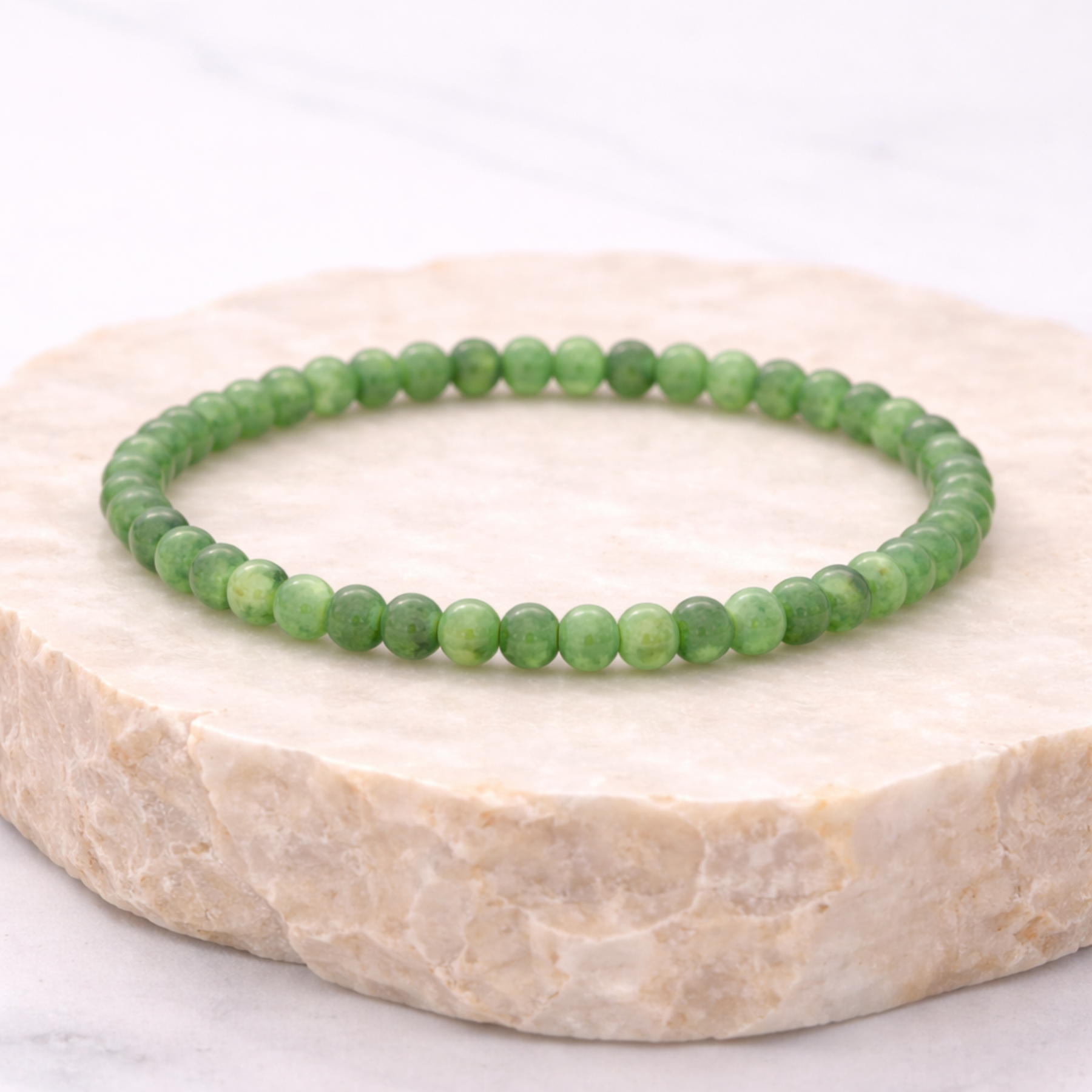 Emerald green jade bracelet on natural stone display