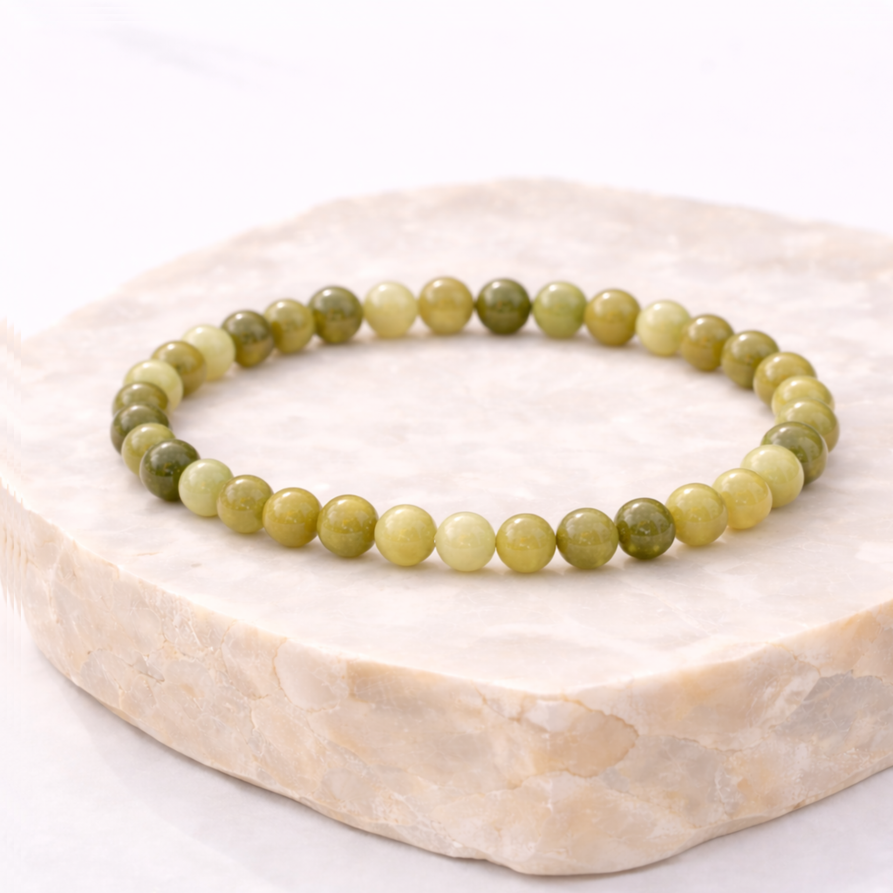 Green jade crystal bead bracelet on natural stone display