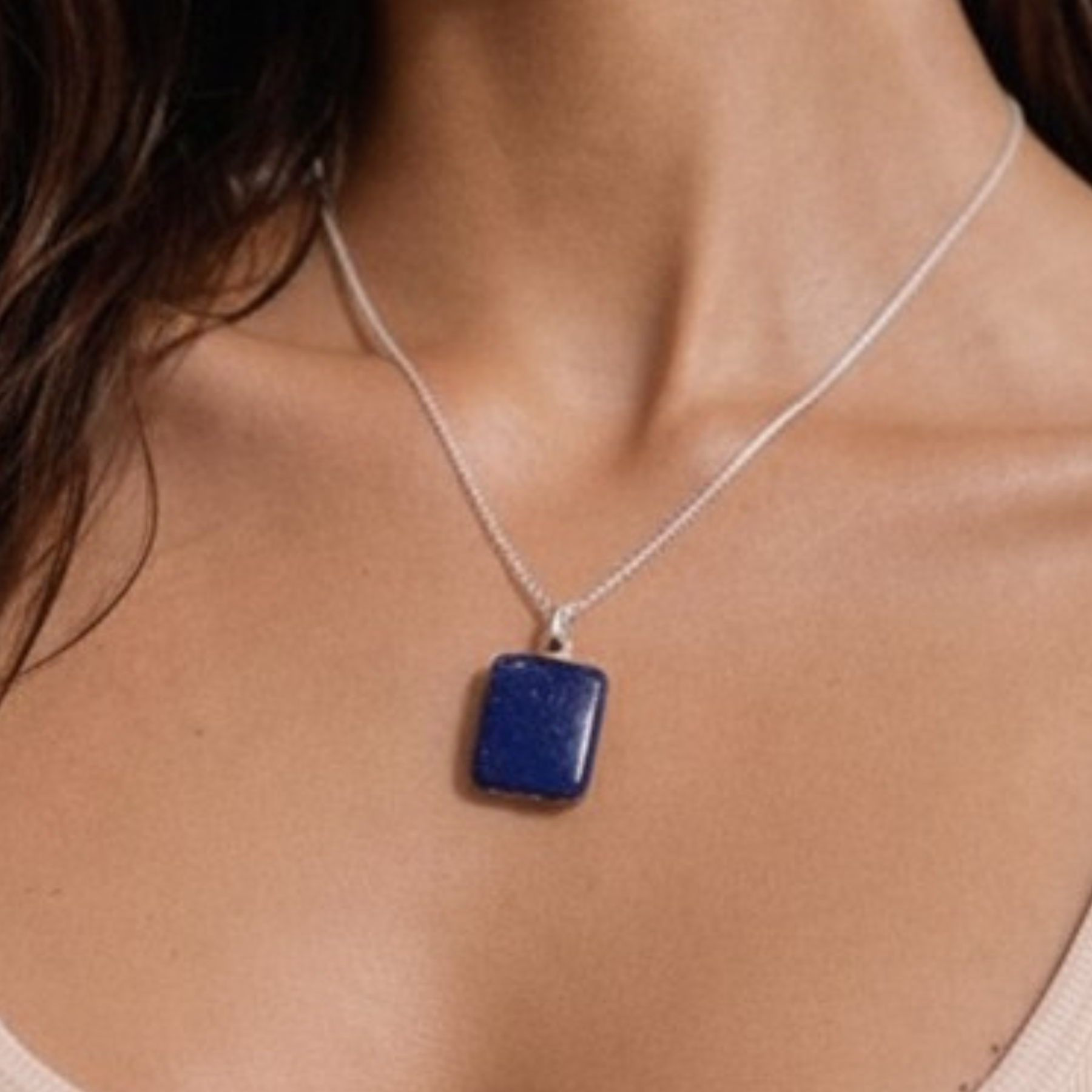 Lapis lazuli necklace close up on model showing square blue stone pendant