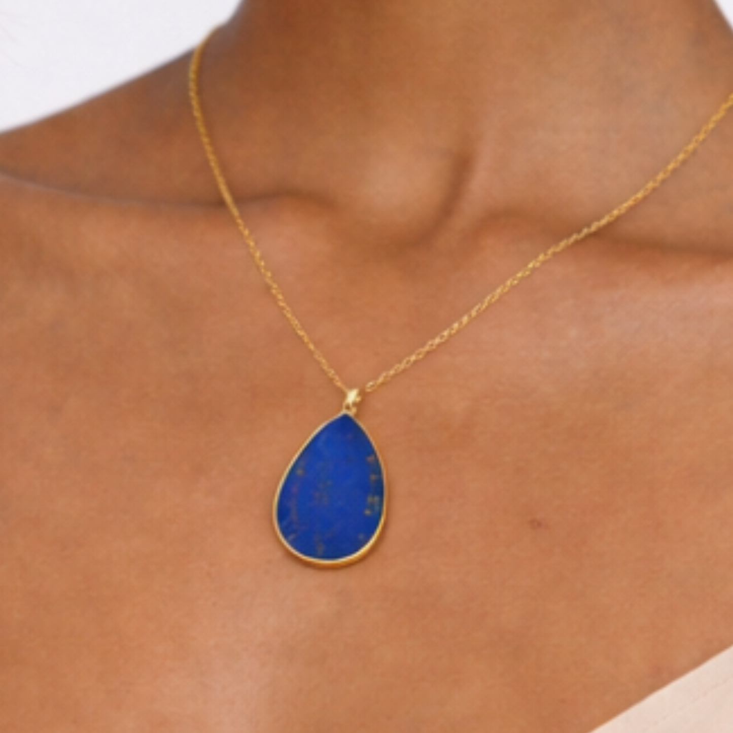 Lapis lazuli pendant necklace close up on model showing gold chain and blue pendant