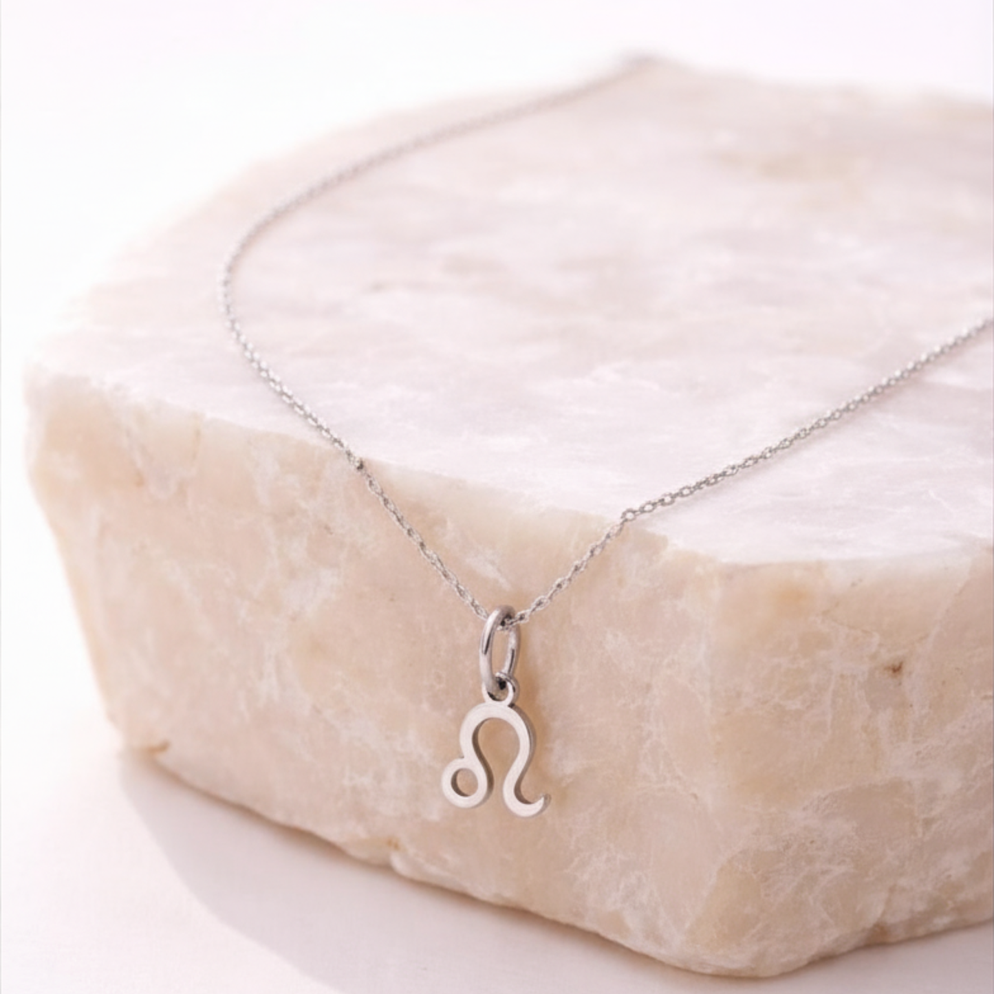 Leo zodiac necklace silver pendant on beige stone slab
