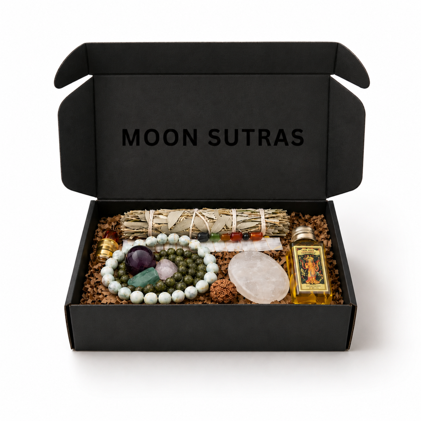Moon Sutras ritual box displayed open on a white background featuring green mala beads, a light blue Shoushan bracelet, moonstone palm stone, ritual oil, sage bundle, rudraksha seed, chakra crystal wand and spiritual ritual tools.