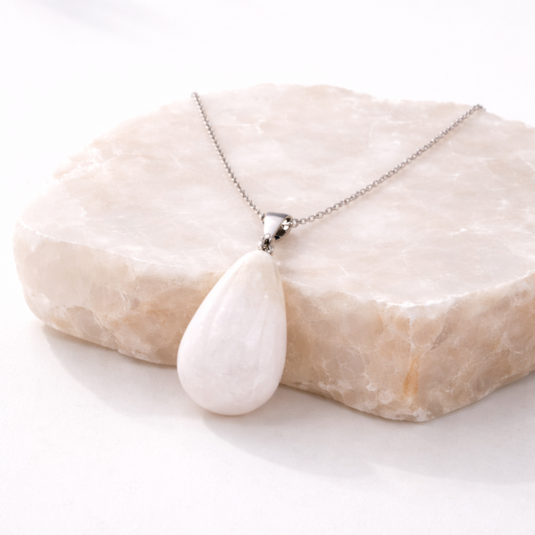 Moonstone necklace teardrop white stone pendant on beige stone slab