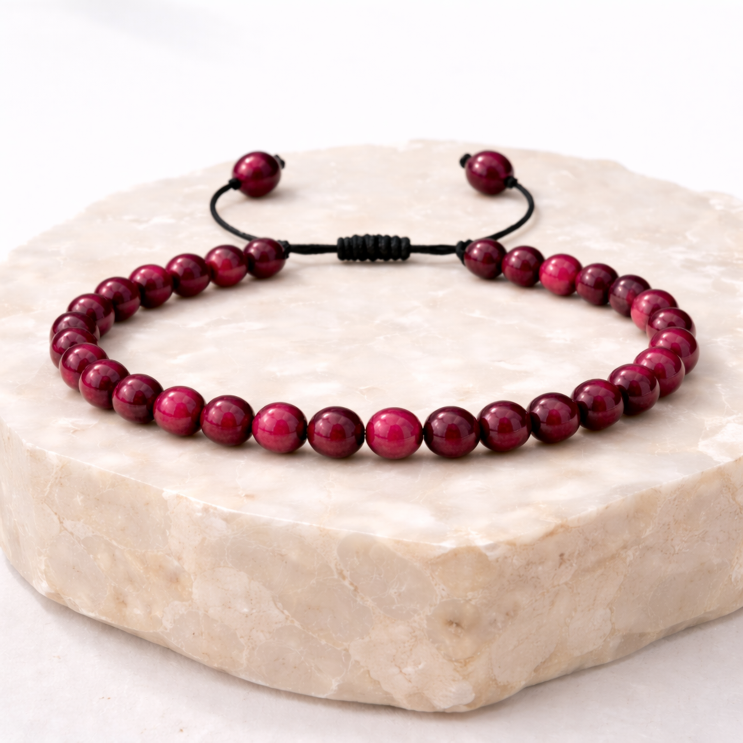 Pink tiger’s eye bracelet with polished beads on natural stone display