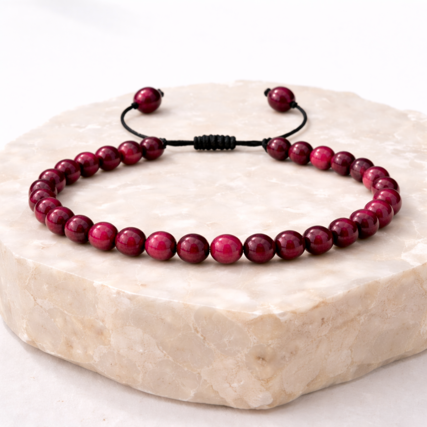 Pink tiger’s eye bracelet with polished beads on natural stone display