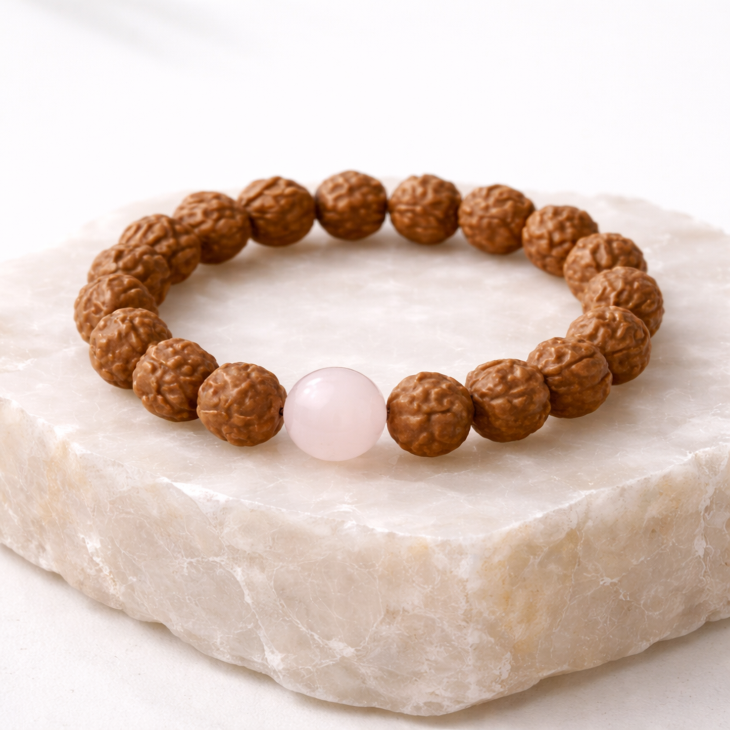 Rudraksha bead bracelet with rose quartz gemstone on natural stone base