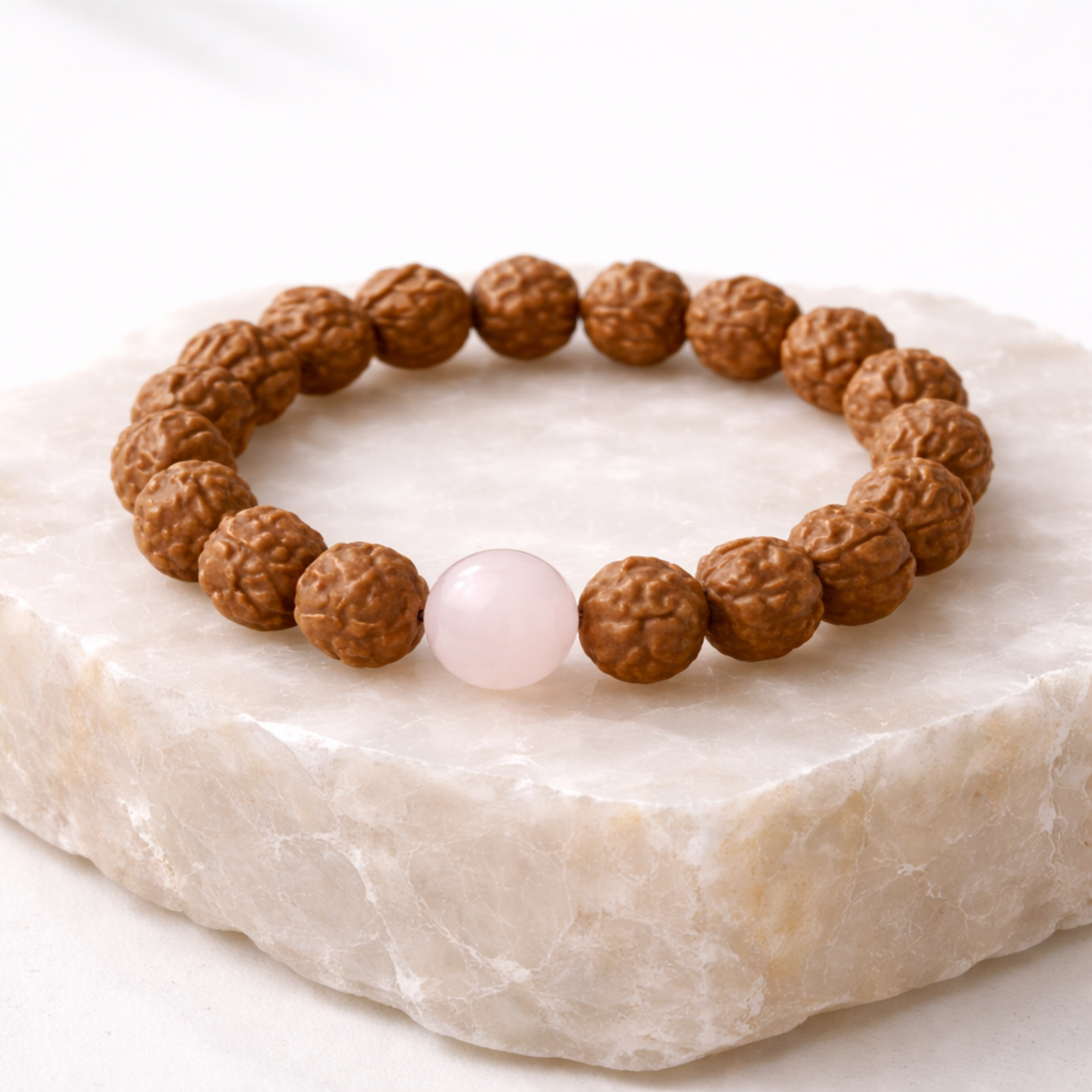 Rudraksha bead bracelet with rose quartz gemstone on natural stone base