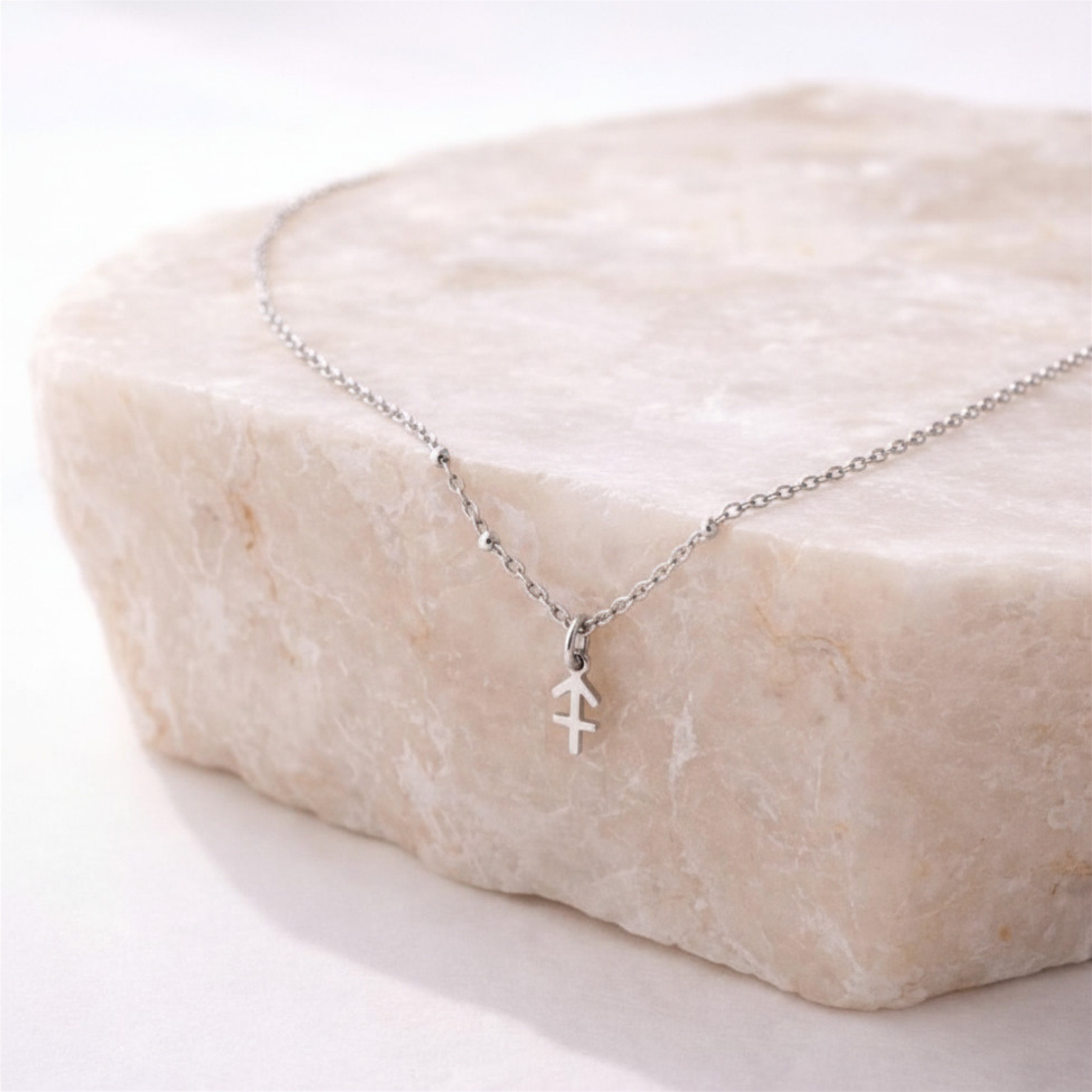 Sagittarius zodiac necklace silver pendant on beige stone slab