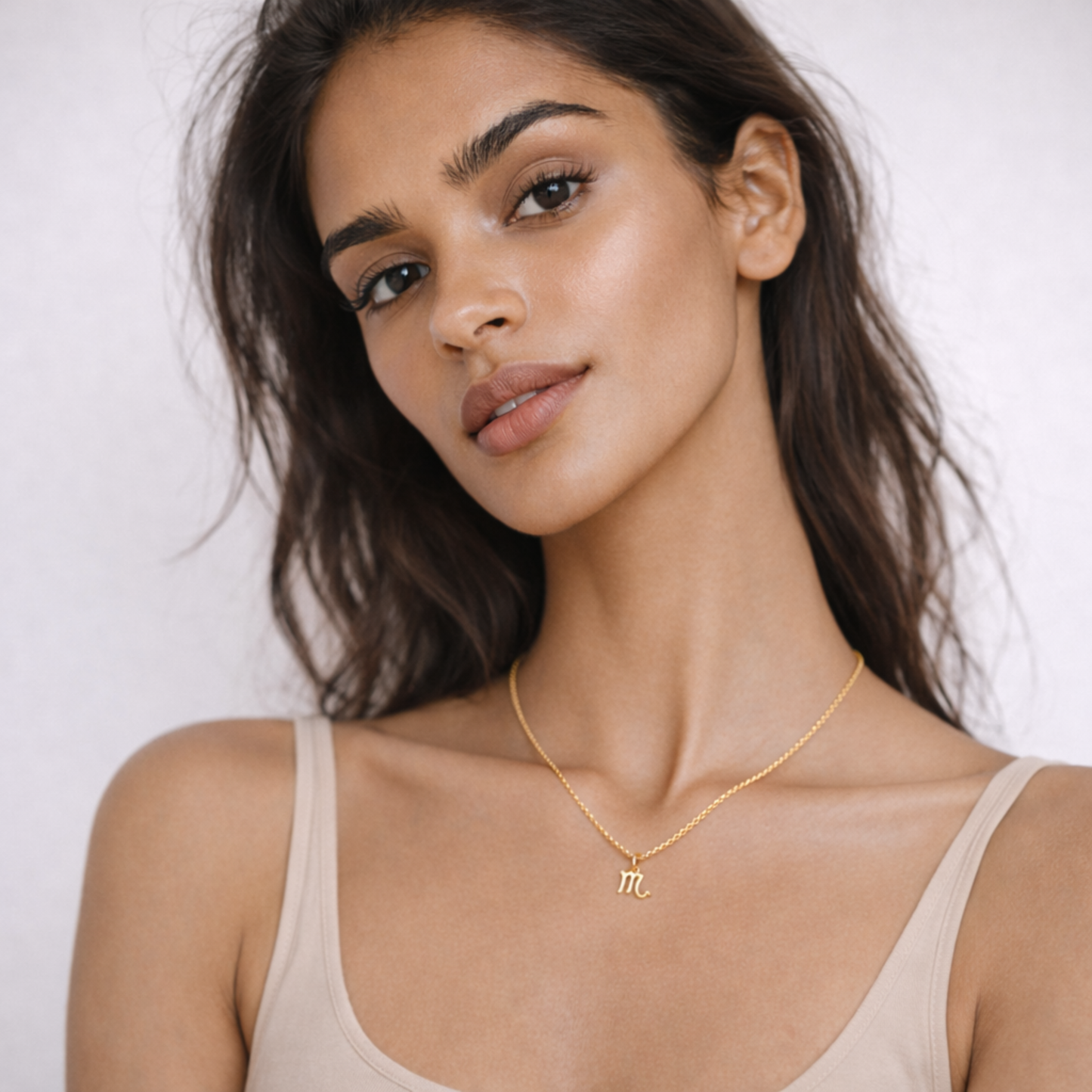 Scorpio zodiac necklace gold worn on model with beige top