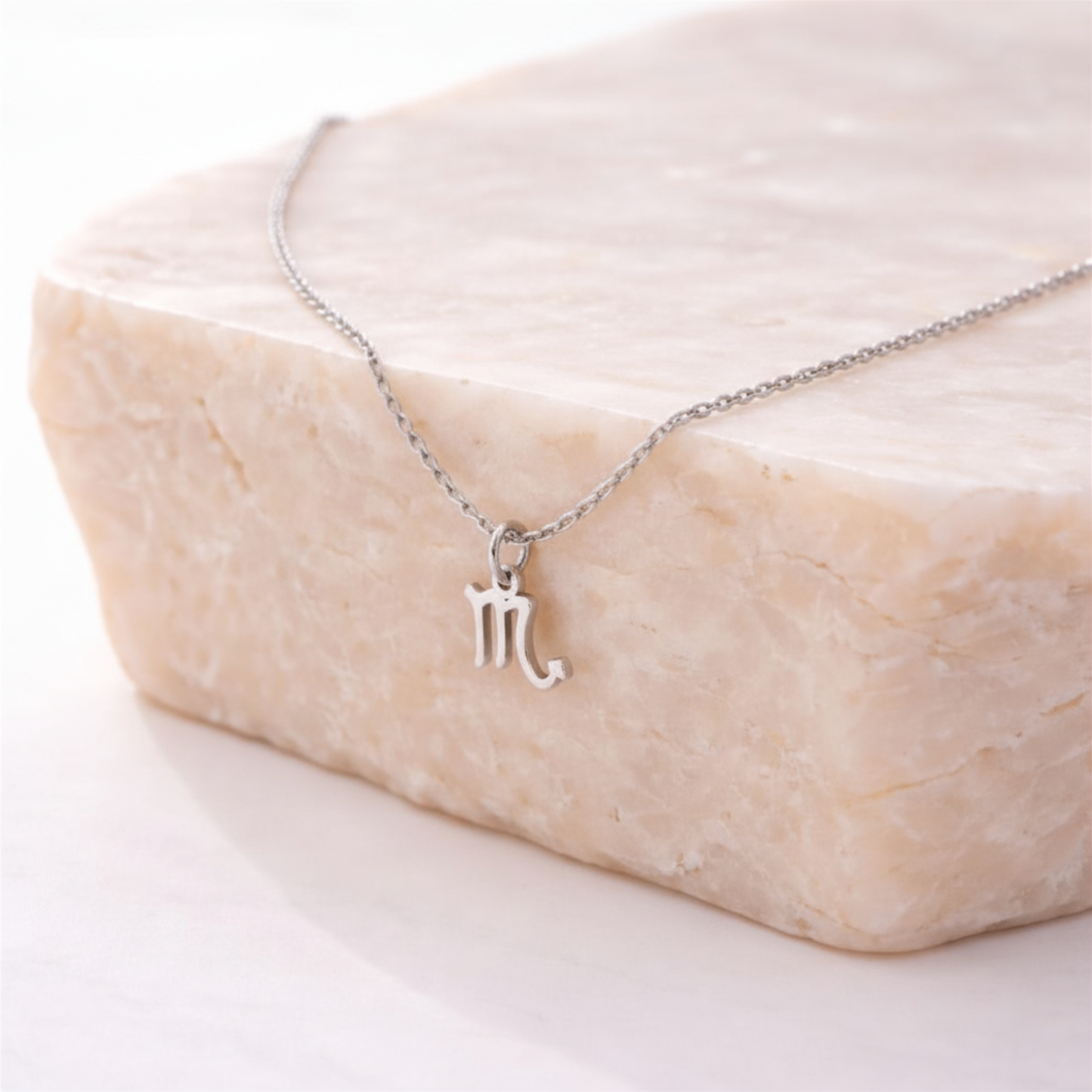 Scorpio zodiac necklace silver pendant on beige stone slab