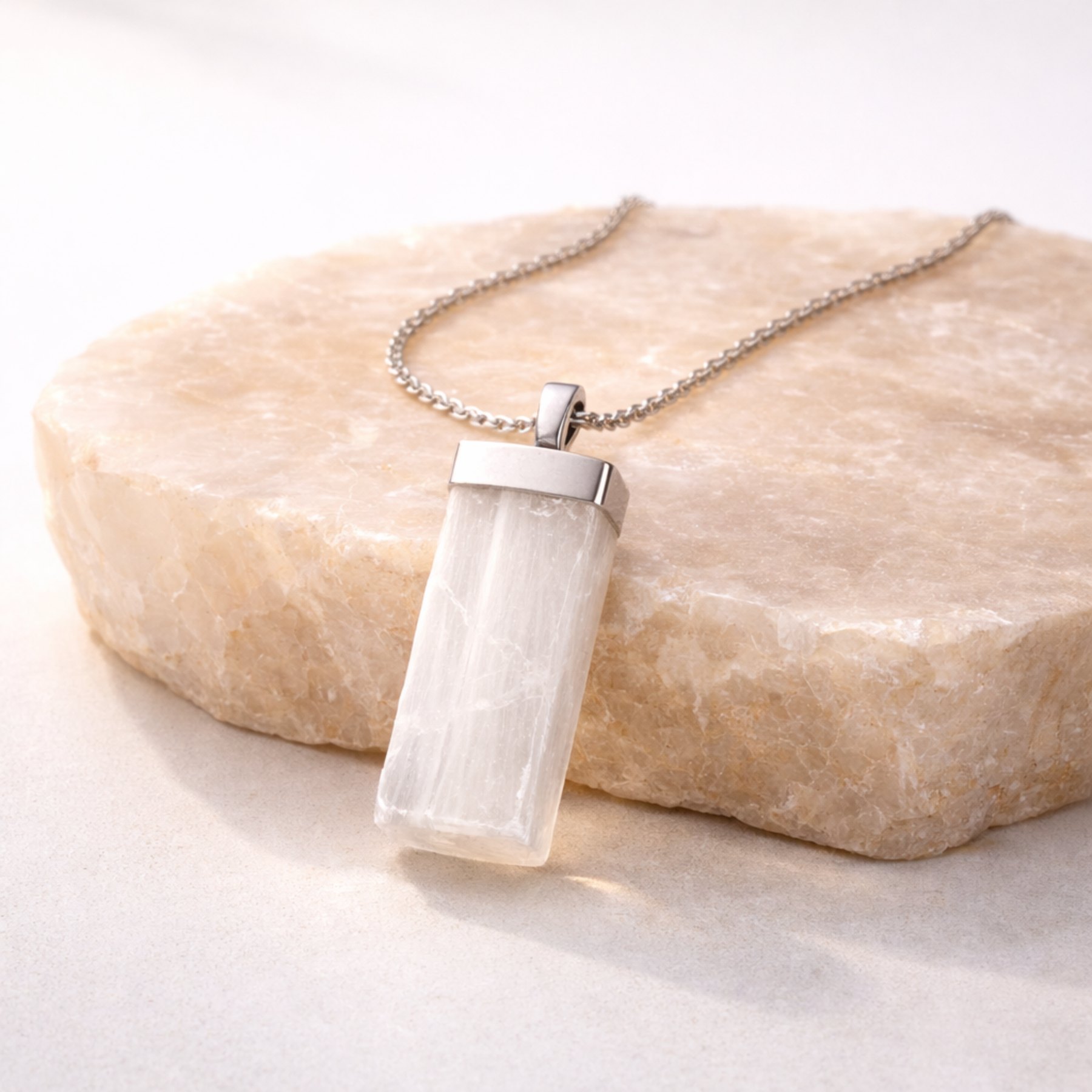 Selenite necklace rectangular white crystal pendant on beige stone slab