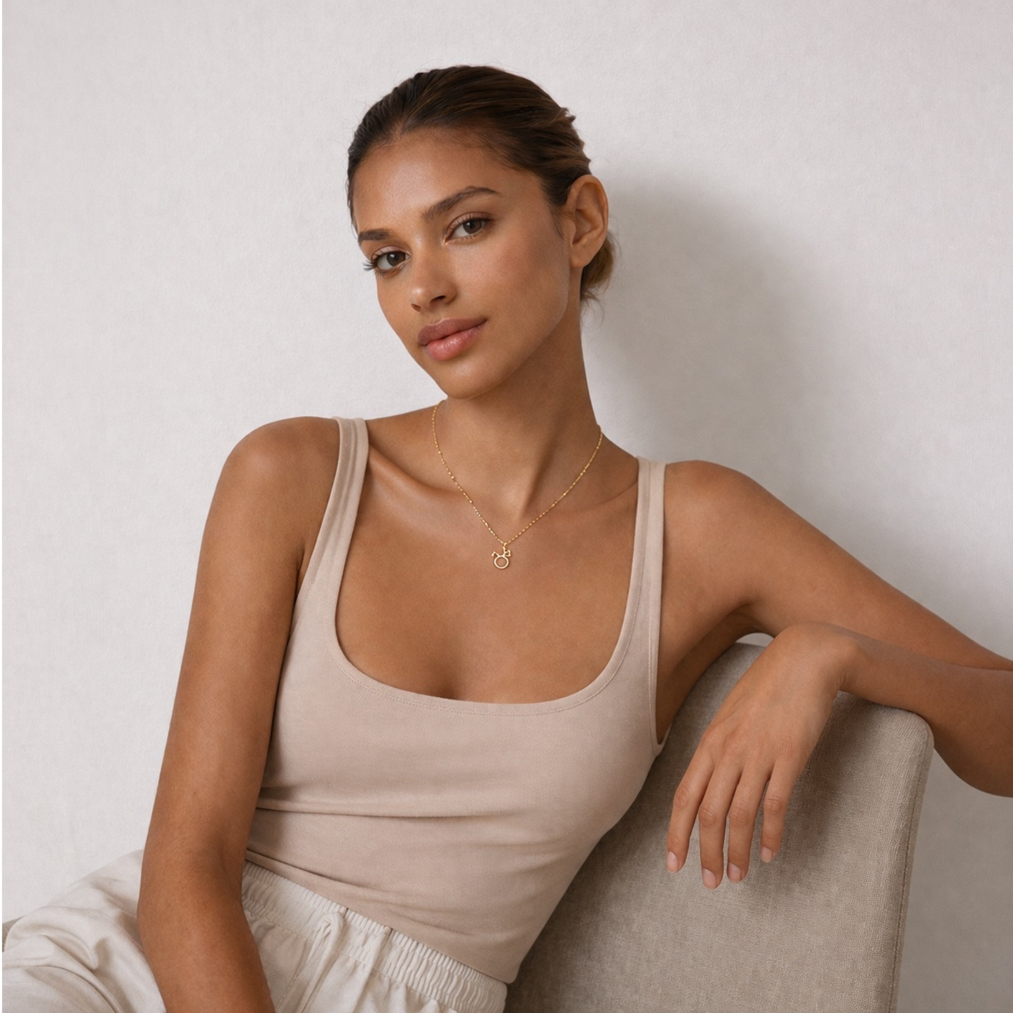 Taurus zodiac necklace gold worn on model sitting down