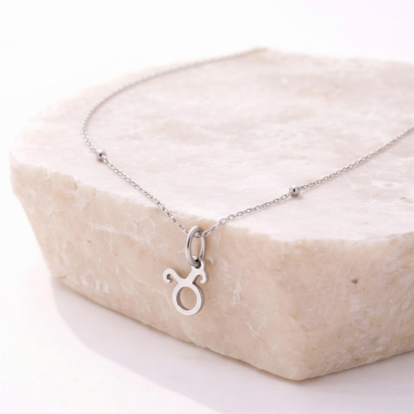 Taurus zodiac necklace silver pendant on beige stone slab