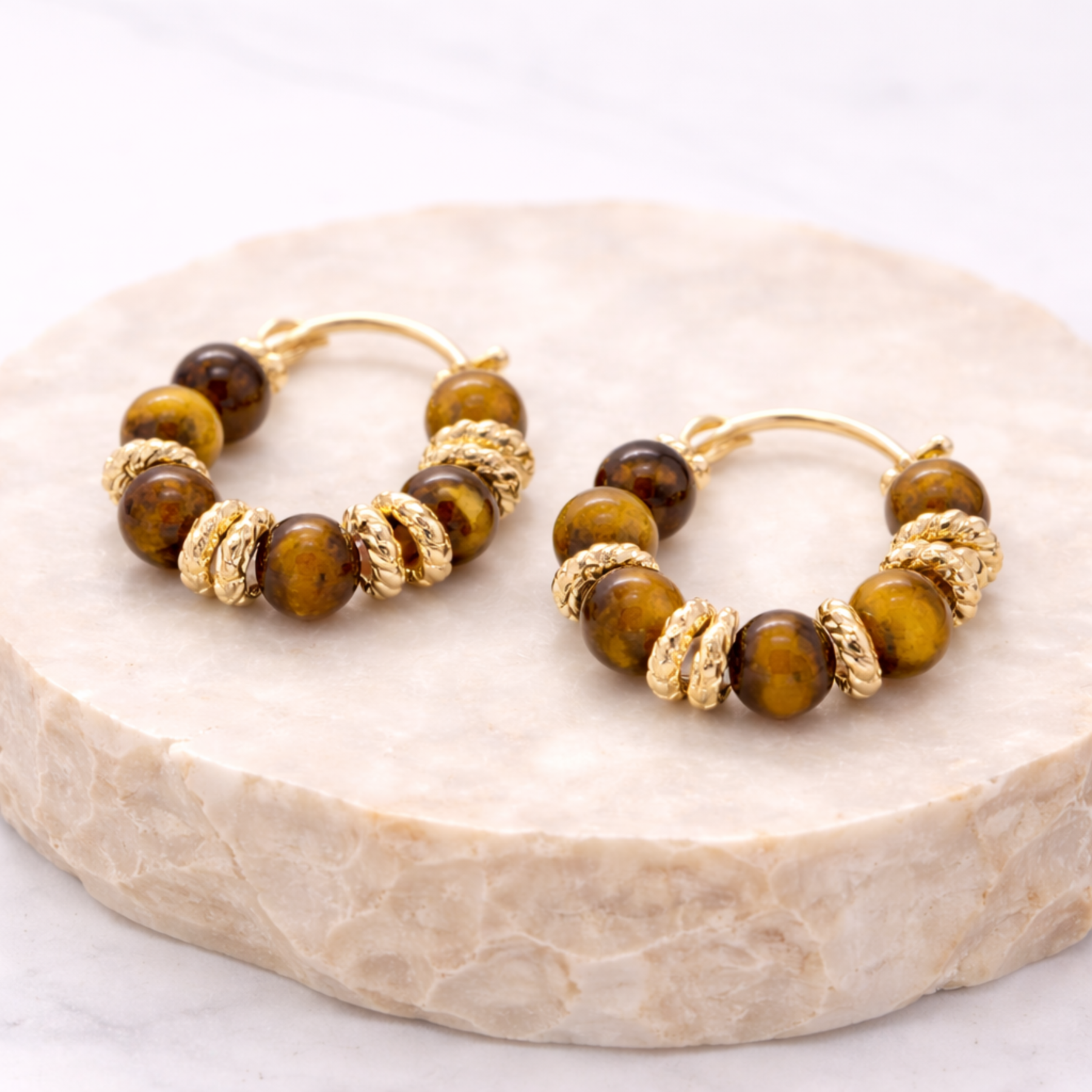 Tiger’s Eye hoop earrings on natural stone display