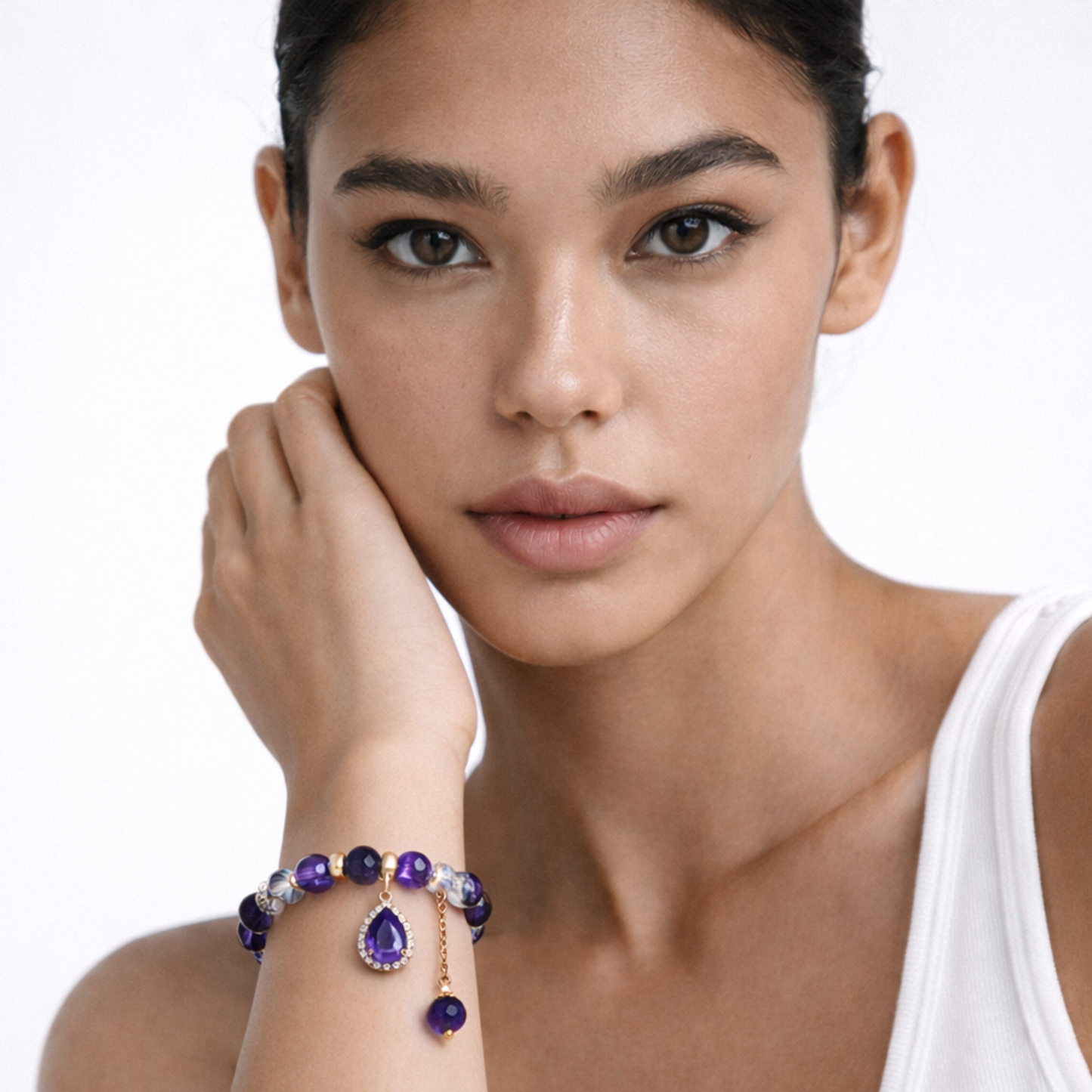 Woman wearing amethyst pendant bracelet with purple beads and gold charm jewellery