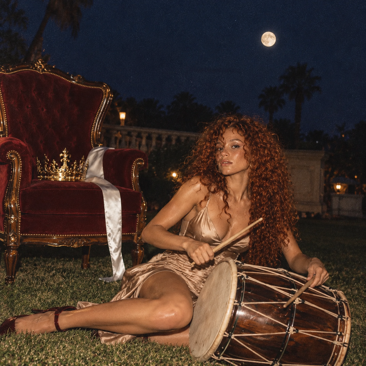 Curly red-haired woman in a champagne satin dress looking towards the camera while playing a wooden drum beside a burgundy velvet throne and gold crown beneath a moonlit sky.